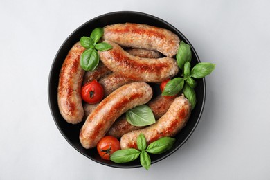 Photo of Bowl with tasty homemade sausages, basil leaves and tomatoes on grey table, top view