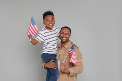 Photo of 4th of July - Independence Day of USA. Happy man and his son with American flags on light grey background