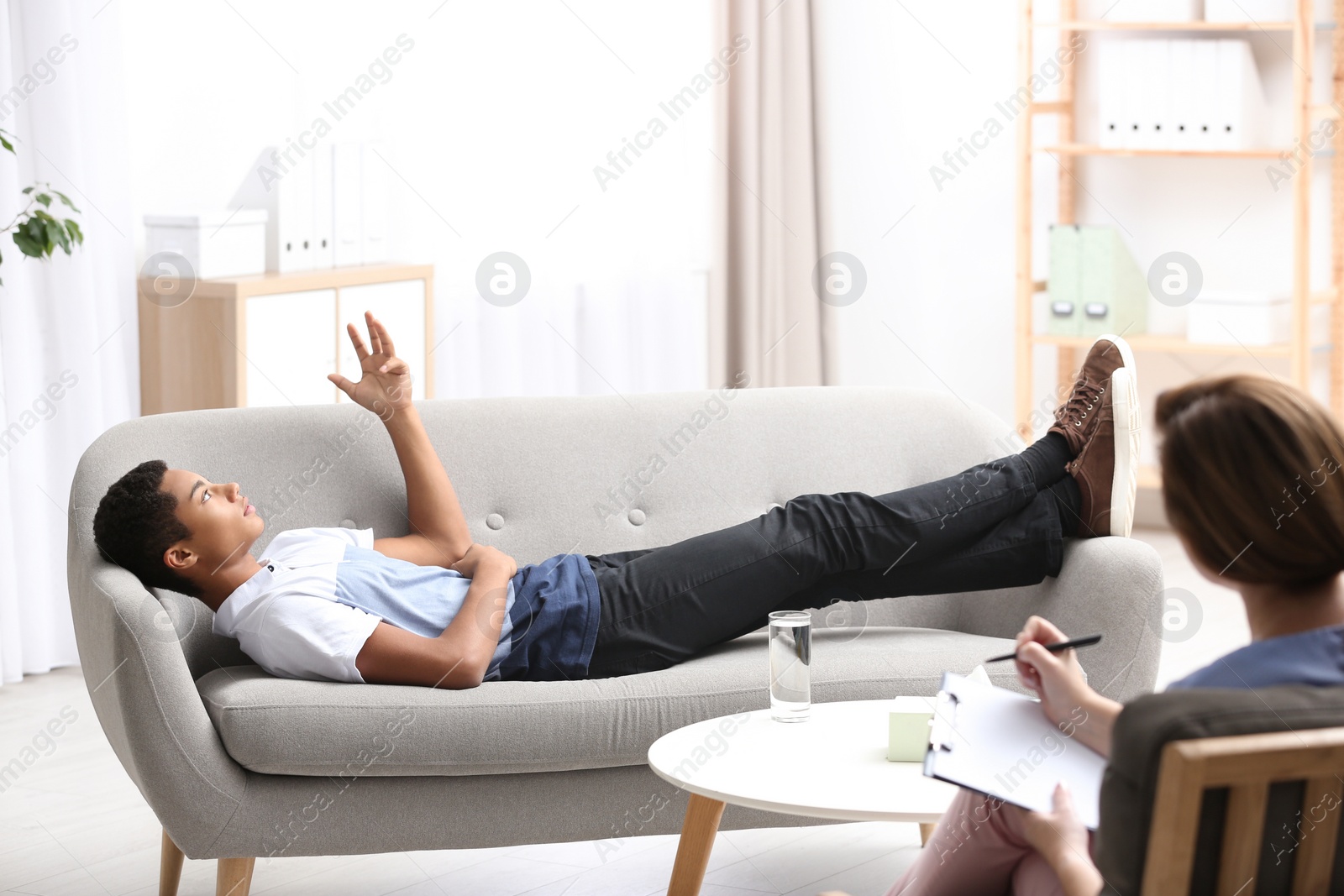 Photo of Psychotherapist working with African-American teenage boy in office