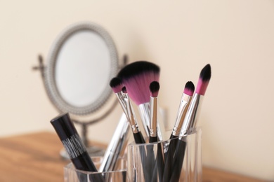 Photo of Organizer with cosmetic products for makeup on table against blurred background, closeup