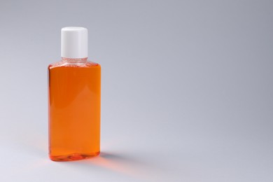 Photo of Fresh mouthwash in bottle on grey background, closeup. Space for text