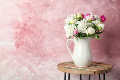 Vase with bouquet of beautiful flowers on table against color background