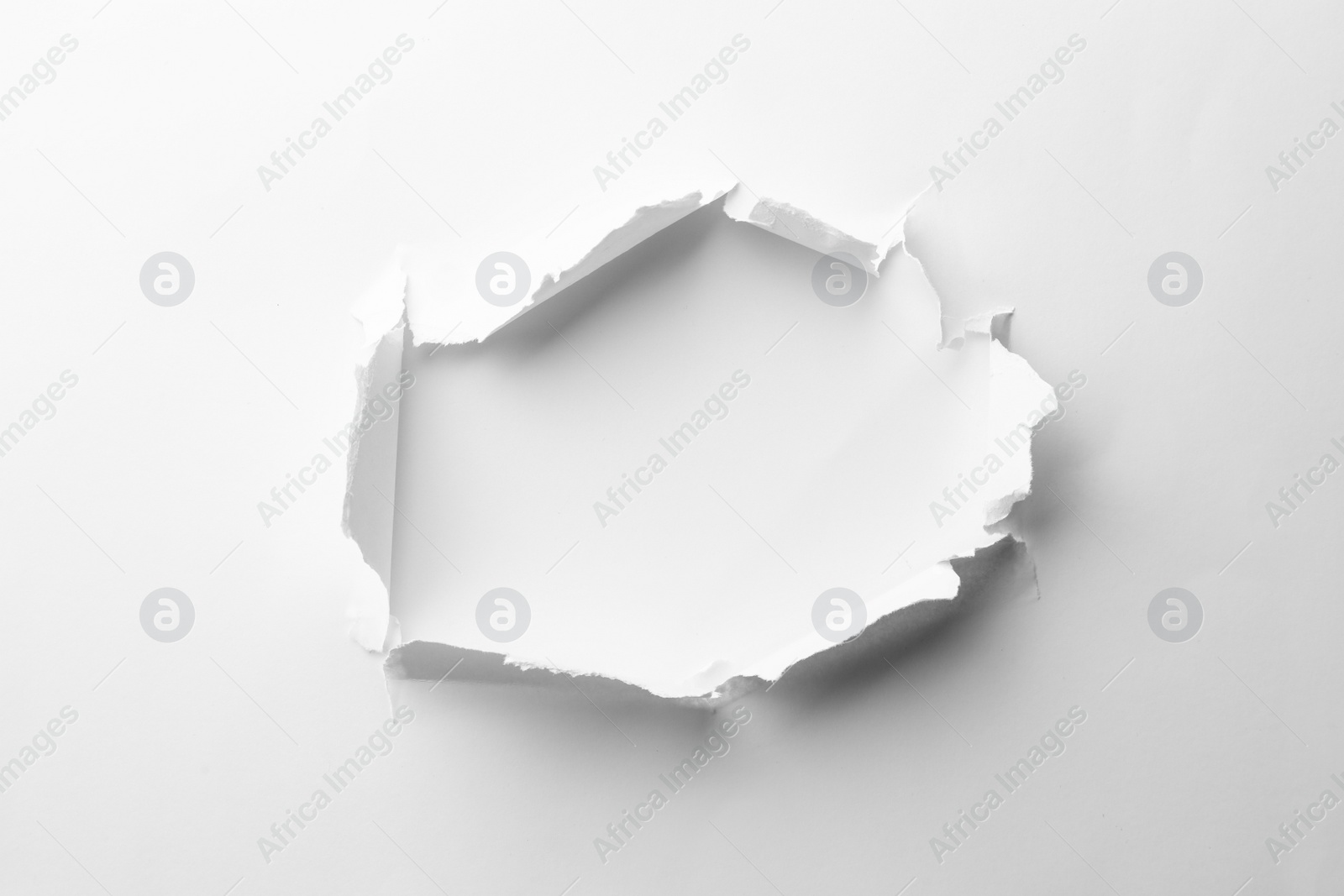 Photo of Hole in white paper on light background