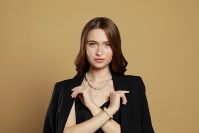 Photo of Young woman wearing elegant pearl jewelry on brown background