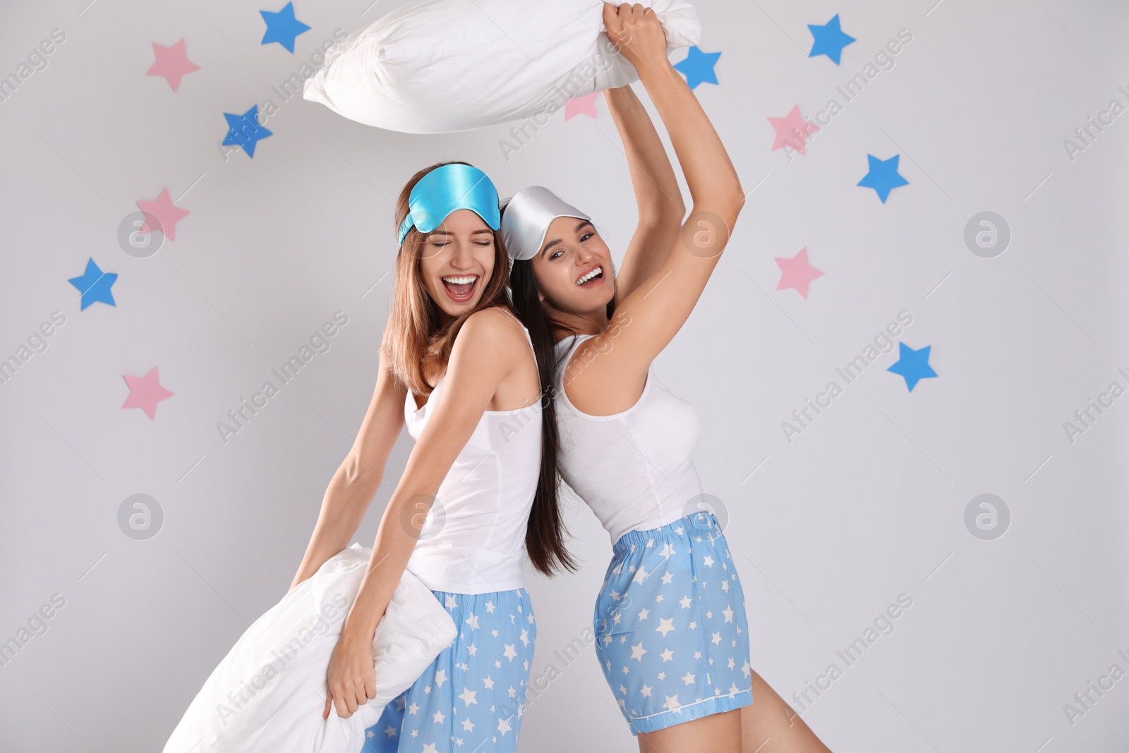 Photo of Beautiful women with pillows on light grey  background. Bedtime