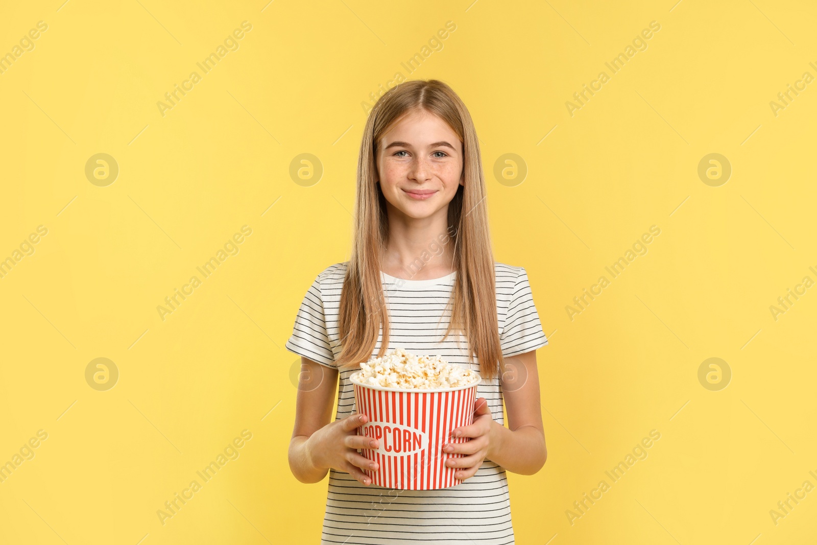 Photo of Teenage girl with popcorn during cinema show on color background