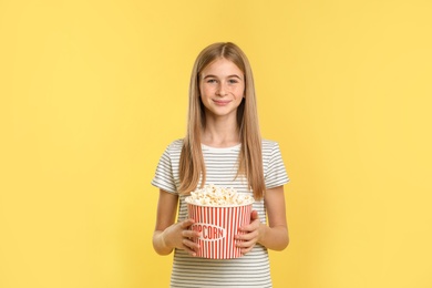 Teenage girl with popcorn during cinema show on color background