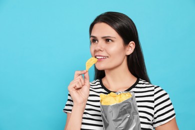 Photo of Beautiful woman eating potato chips on light blue background. Space for text