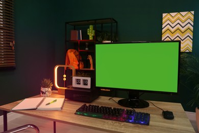Modern computer and RGB keyboard on wooden table indoors. Mockup green screen
