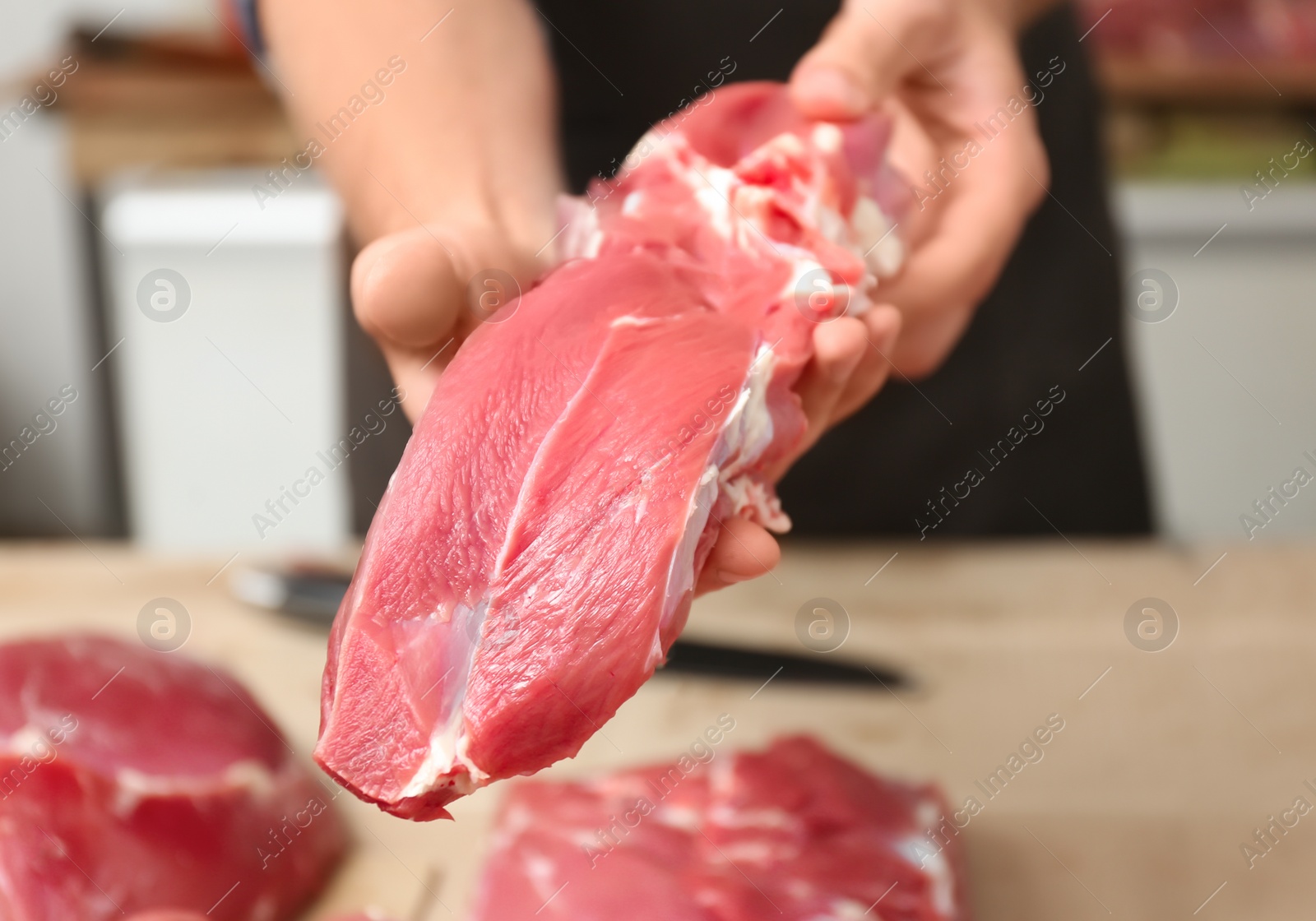 Photo of Male butcher holding fresh raw meat in shop, closeup