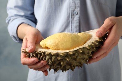 Photo of Woman with piece of fresh ripe durian against blue background, closeup