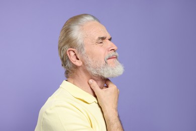 Photo of Senior man suffering from sore throat on light purple background. Cold symptoms