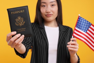 Photo of Immigration to United States of America. Woman with passport and flag on orange background, selective focus