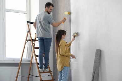 Woman and man hanging wallpaper in room