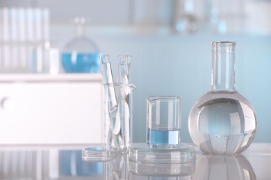 Laboratory analysis. Different glassware with liquid on white table indoors, space for text