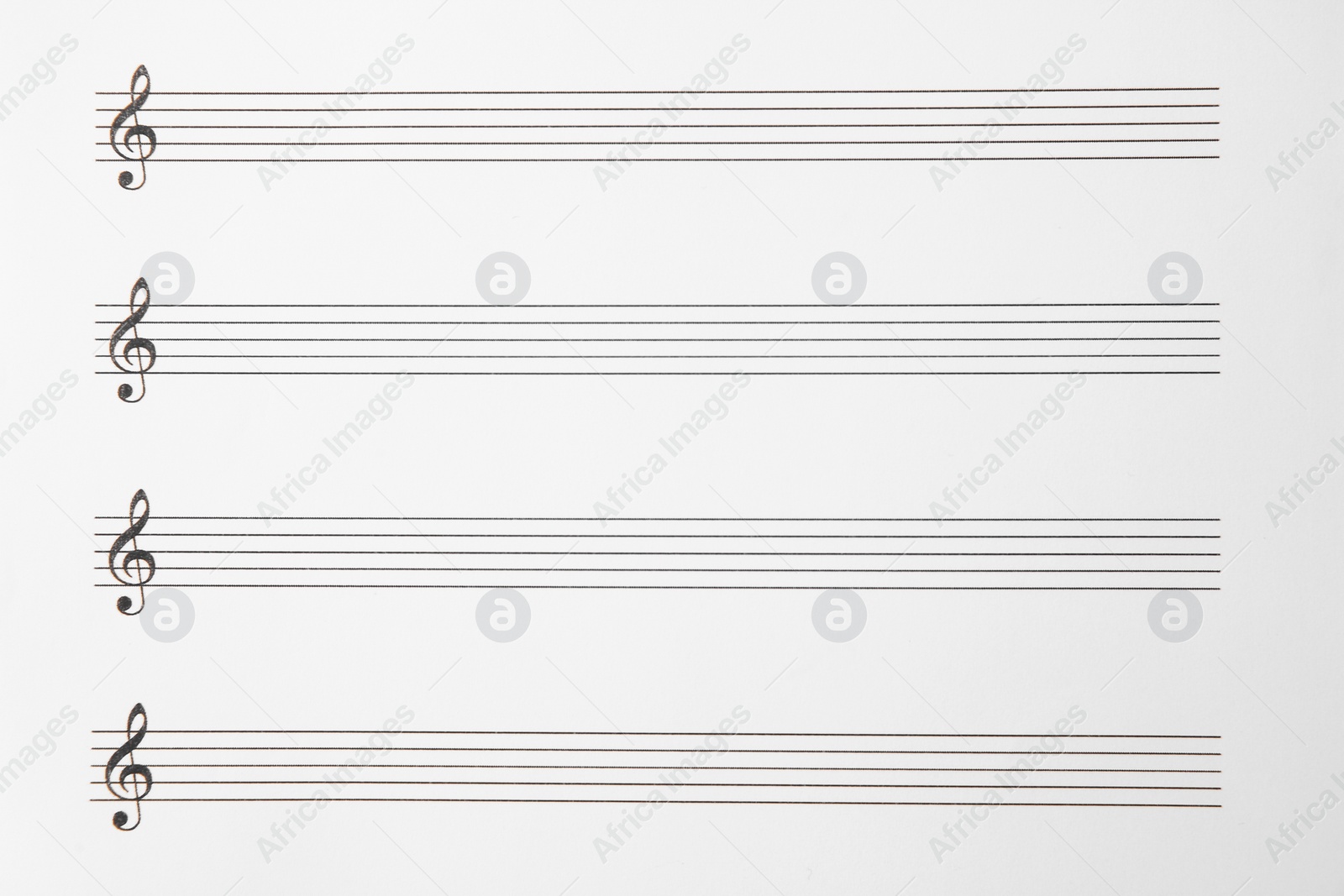 Photo of Sheet with empty staves for music notes and treble clef as background, top view