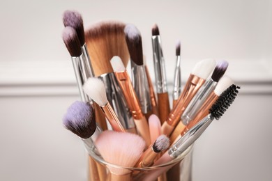 Photo of Set of professional makeup brushes on blurred background, closeup
