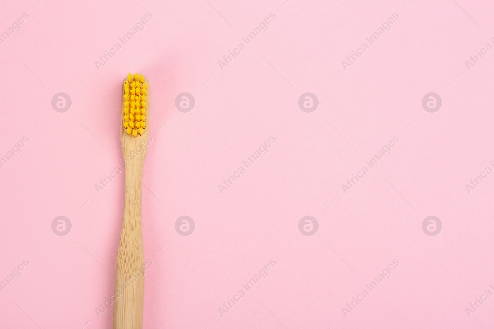 Photo of Toothbrush made of bamboo on pink background, top view. Space for text