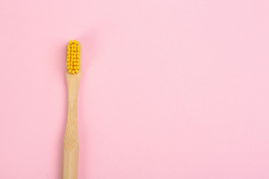 Toothbrush made of bamboo on pink background, top view. Space for text