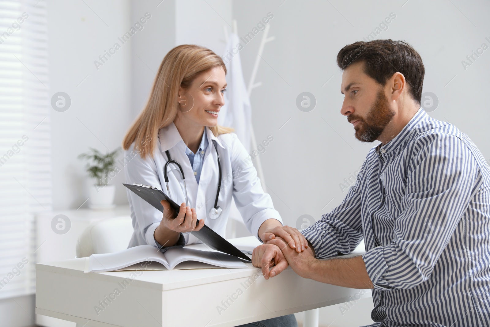 Photo of Doctor consulting patient at white table in clinic