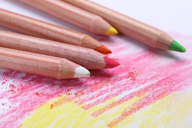 Photo of Colorful pastel pencils and scribbles on white background, closeup. Drawing supplies