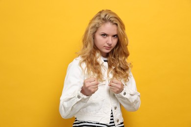 Photo of Young woman ready to fight on yellow background