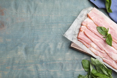 Photo of Flat lay composition with sliced raw bacon on light blue wooden table. Space for text