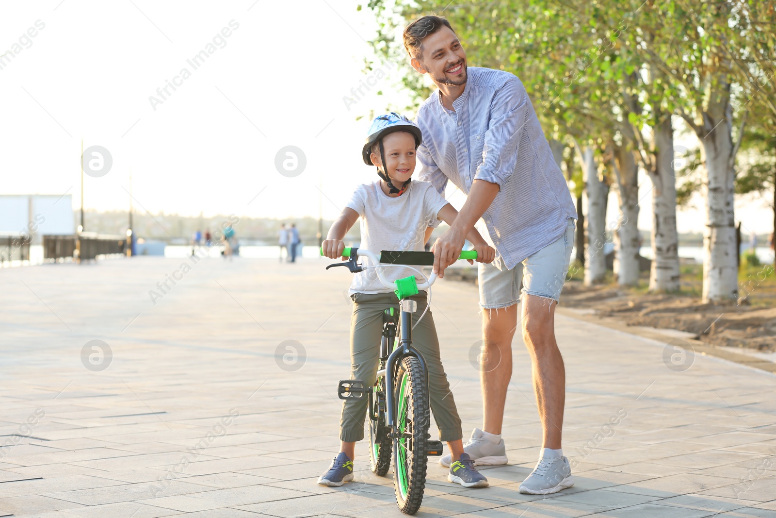 Photo of Father teaching son to ride bicycle on street