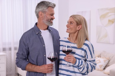 Photo of Happy affectionate couple with glasses of wine at home. Romantic date