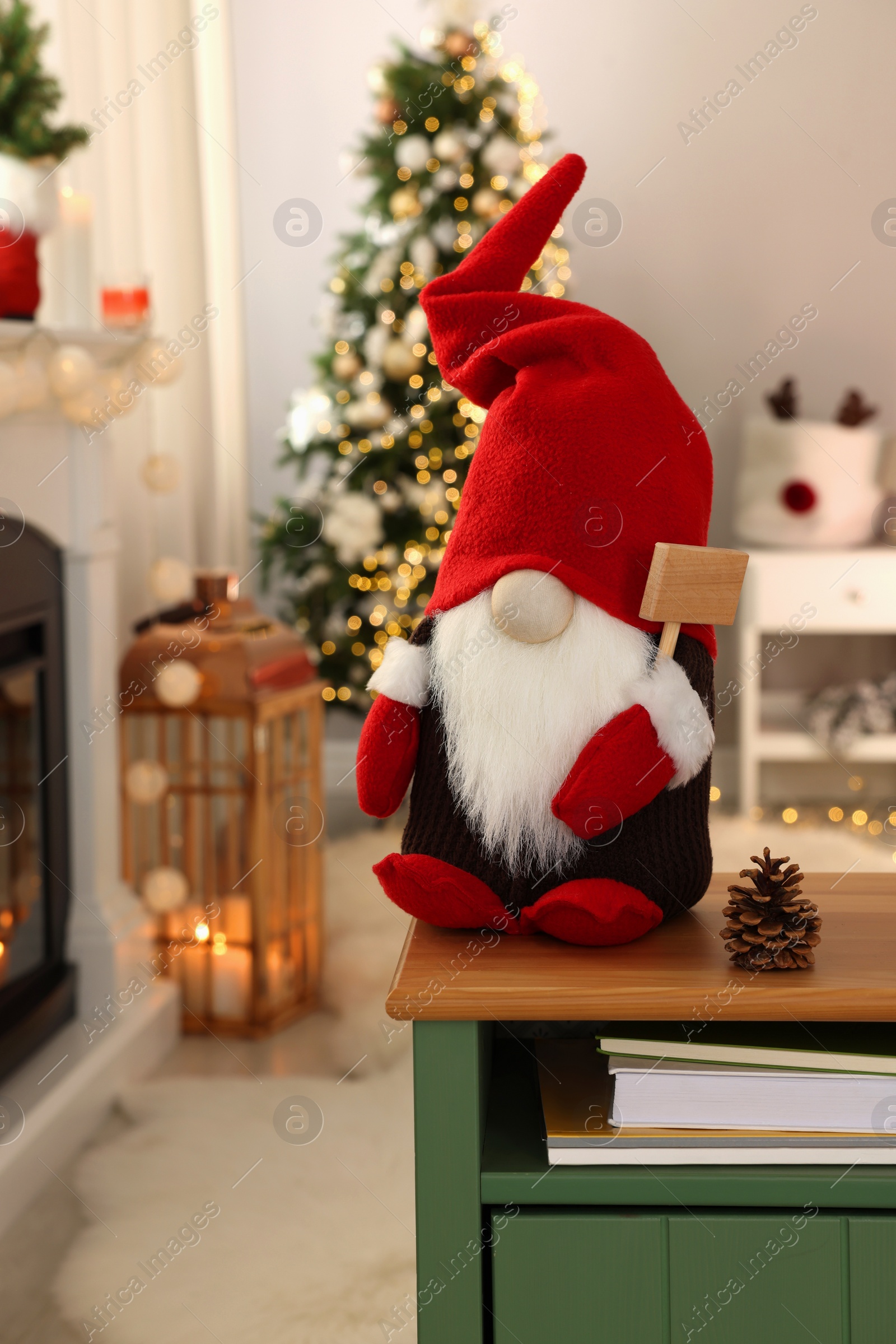 Photo of Cute Christmas gnome on wooden table in room with festive decorations