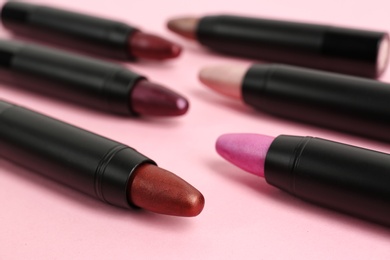 Photo of Set of bright lipsticks in black tubes on pink background