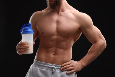 Young man with muscular body holding shaker of protein on black background, closeup