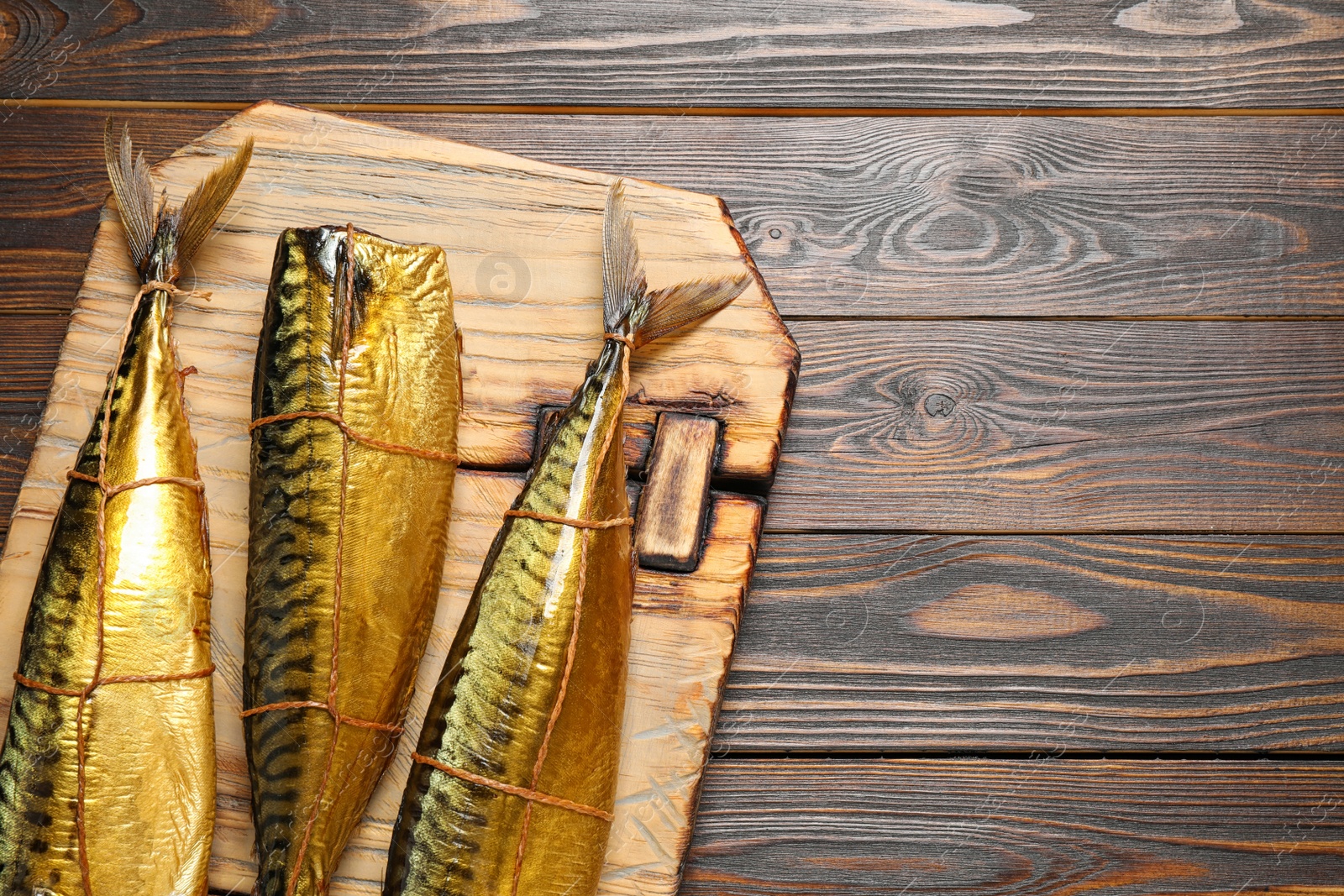 Photo of Tasty smoked fish on wooden table, top view. Space for text