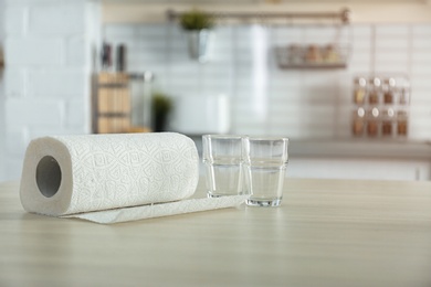 Roll of paper towels and glasses on table in kitchen. Space for text