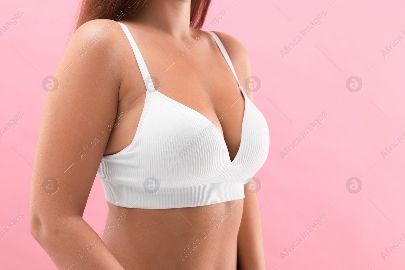 Photo of Woman with beautiful breast on pink background, closeup. Space for text