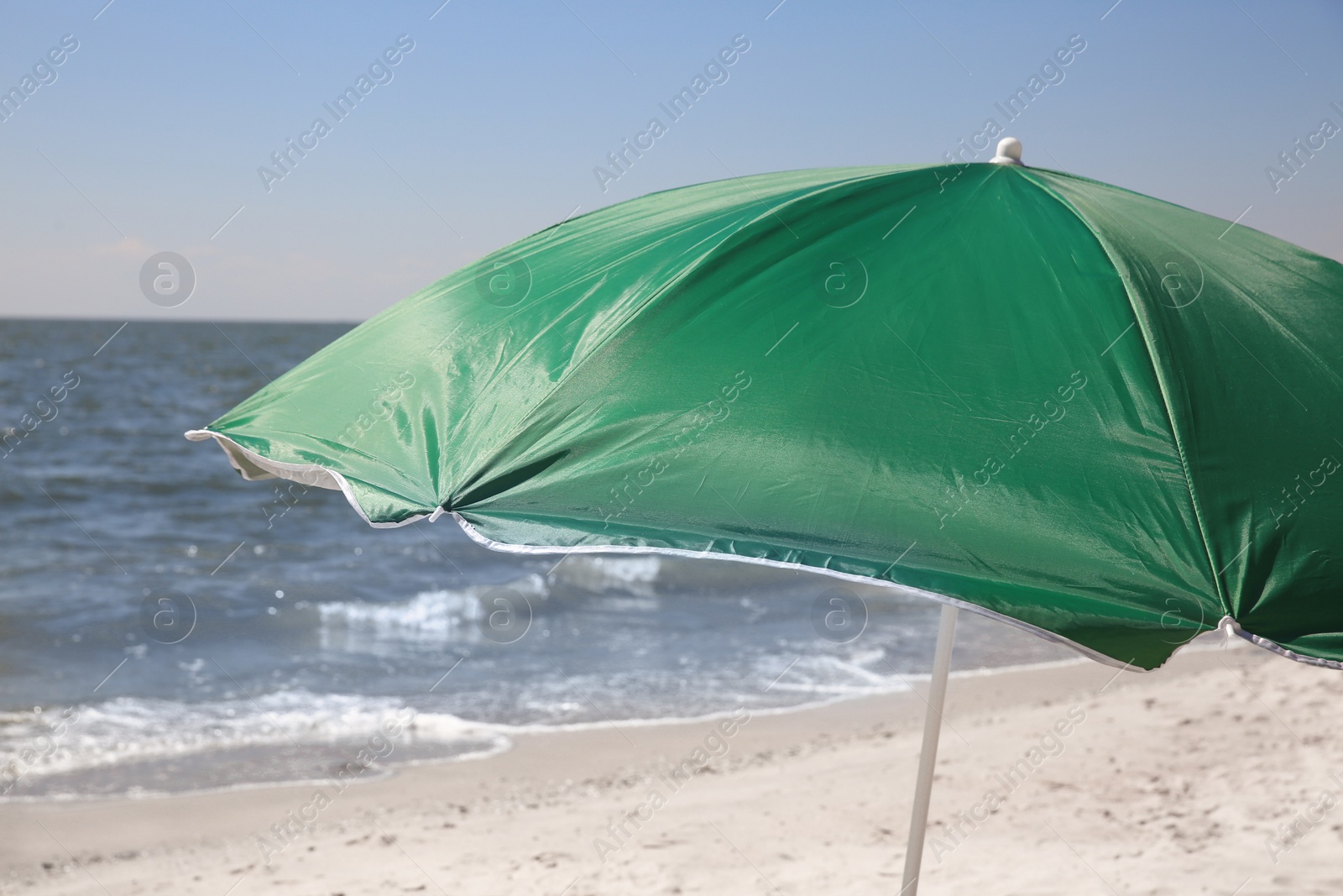 Photo of Green beach umbrella near sea on sunny day