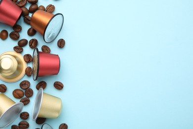 Many coffee capsules and beans on light blue background, flat lay. Space for text