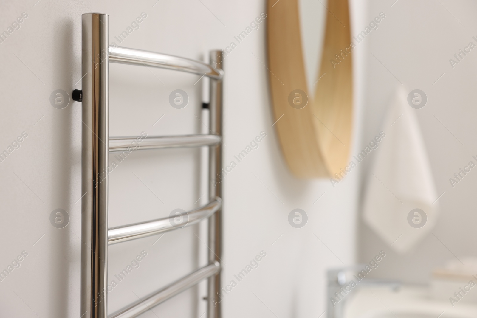 Photo of Heated towel rail on white wall in bathroom, closeup