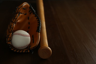 Leather baseball ball, bat and glove on wooden table, space for text