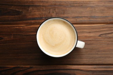 Photo of Tasty cappuccino in cup on wooden table, top view