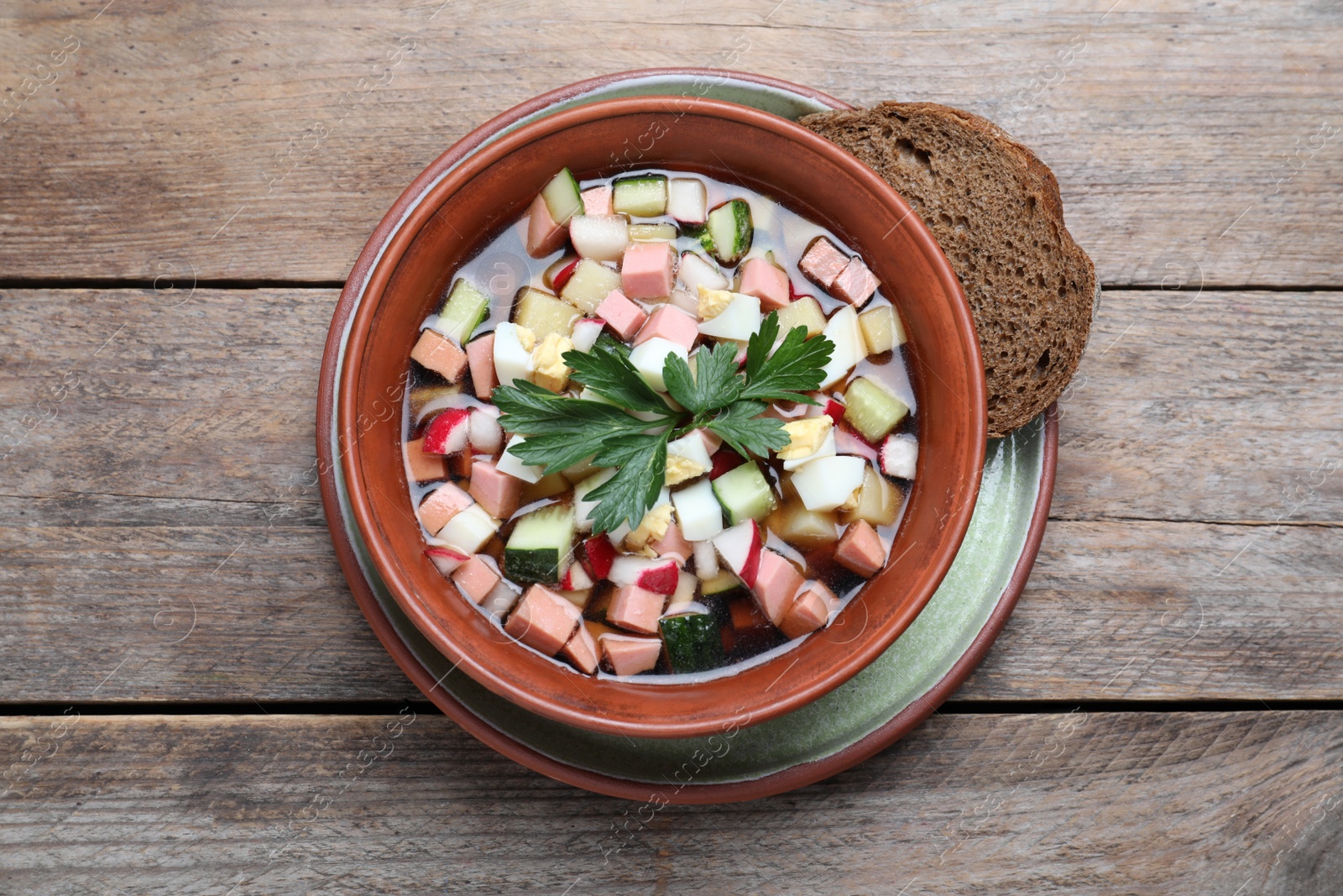 Photo of Delicious cold okroshka with kvass on wooden table, top view. Traditional Russian summer soup