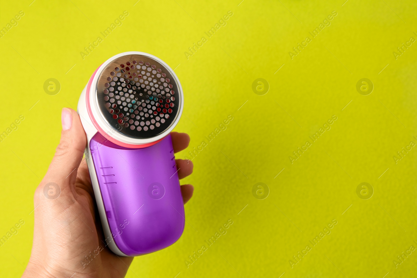 Photo of Woman with fabric shaver on light green background, closeup. Space for text