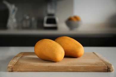 Photo of Delicious ripe mangos on white table in kitchen