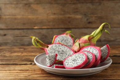 Photo of Delicious cut and whole dragon fruits (pitahaya) on wooden table