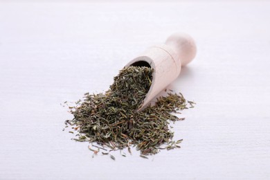 Photo of Scoop with dried thyme on white wooden table, closeup