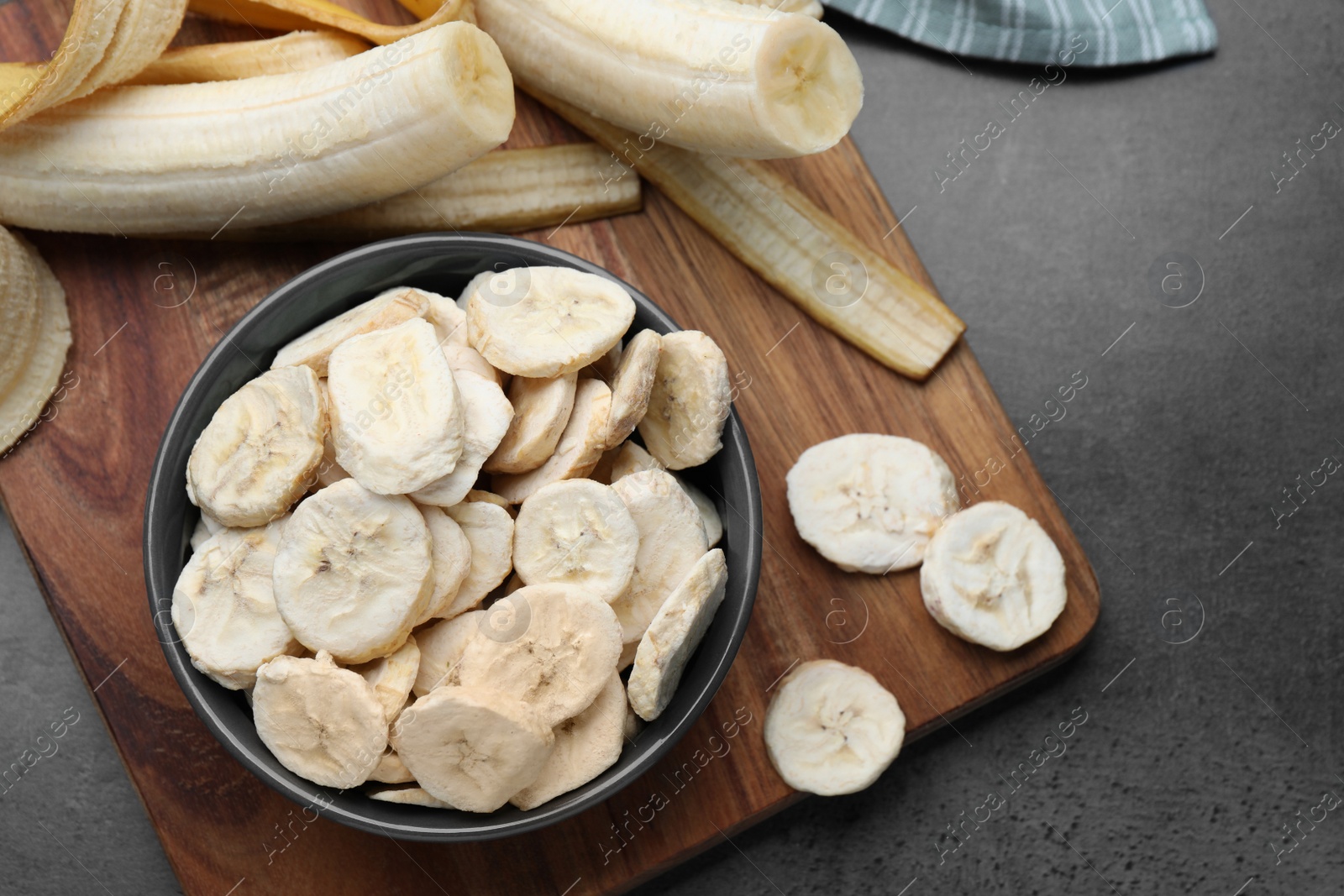 Photo of Freeze dried and fresh bananas on grey table, top view. Healthy lifestyle