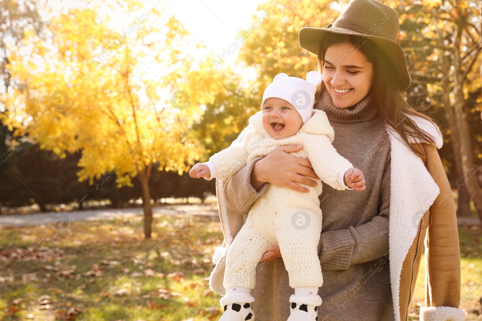 Photo of Happy mother with her baby daughter in park on sunny autumn day, space for text