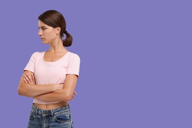 Photo of Resentful woman with crossed arms on violet background, space for text