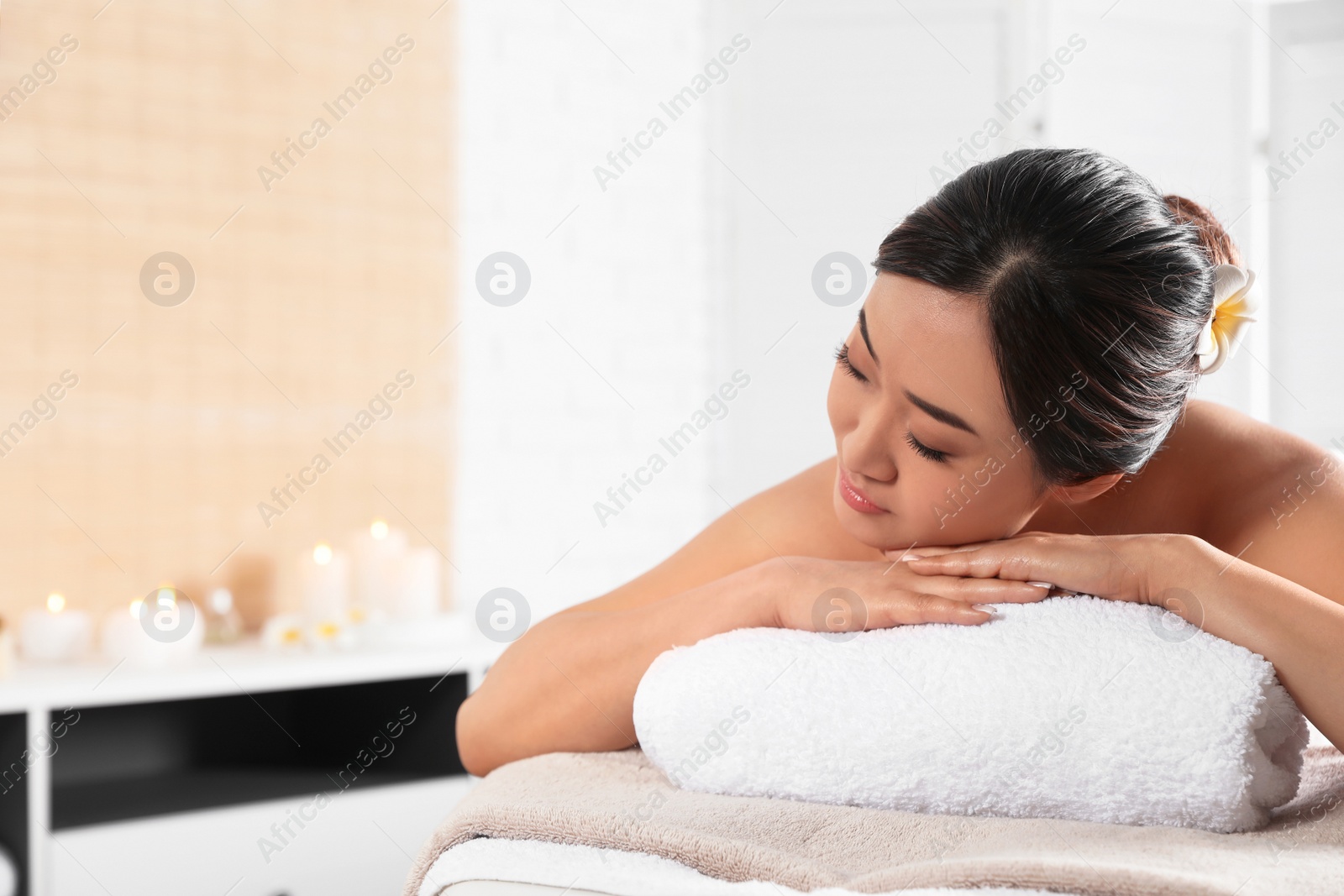 Photo of Beautiful Asian woman lying on massage table in spa salon. Space for text