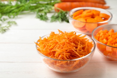 Photo of Bowls of differently cut carrots on white background